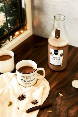 Mok warme chocolademelk op tafel met fles en specerijen