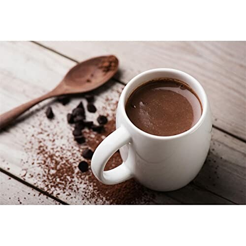 Mok warme chocolademelk met cacaopoeder en lepel op houten tafel.